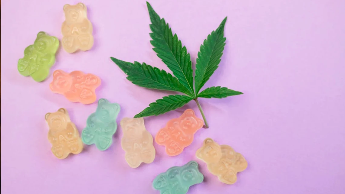Cannabis leaf with 9 colorful, full-spectrum cannabis gummies placed to its left