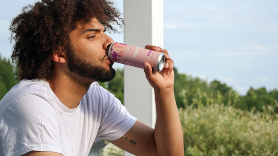 Man drinking Wunder’s Higher Vibes Grapefruit Hibiscus cannabis drink as he looks beyond the porch
