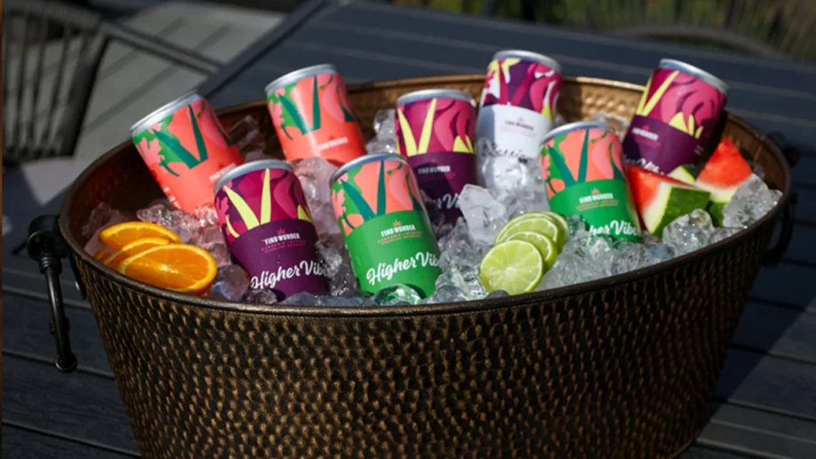 Wunder THC beverages and slices of orange, watermelon, and lime inside basket filled with ice cubes.