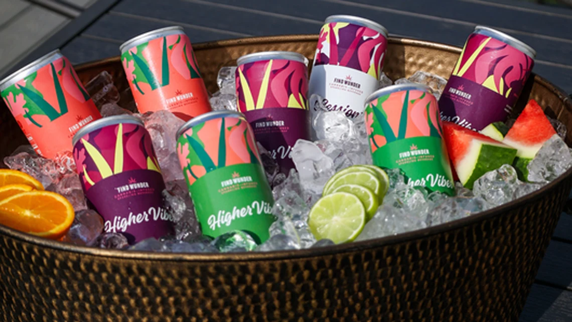 Wunder THC beverages and slices of orange, watermelon, and lime inside basket filled with ice cubes