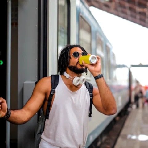 Guy stepping out of a train while sipping a microdosing drink from a can
