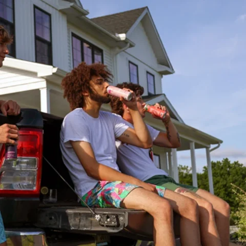 Three guys practicing mindful drinking by sipping Wunder beverages on the back of a pick-up truck