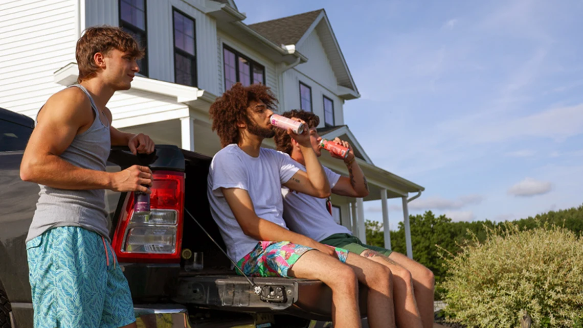Three guys practicing mindful drinking by sipping Wunder beverages on the back of a pick-up truck